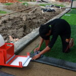 Installation of white joint tape for artificial turf during sports field construction
