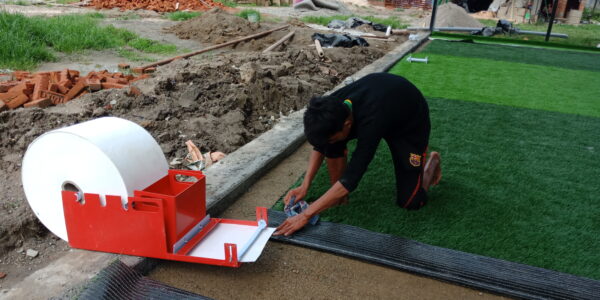 Installation of white joint tape for artificial turf during sports field construction