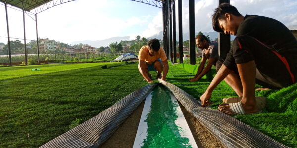 Installation of white joint tape for artificial turf during sports field construction